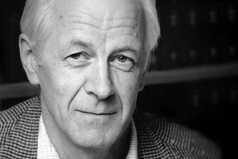 Black and white portrait photo of man with white hair looking at viewer