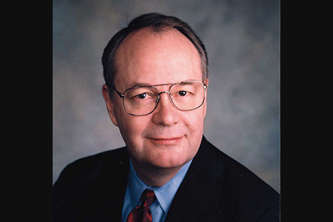 Man with wire rimmed glasses looking back at viewer