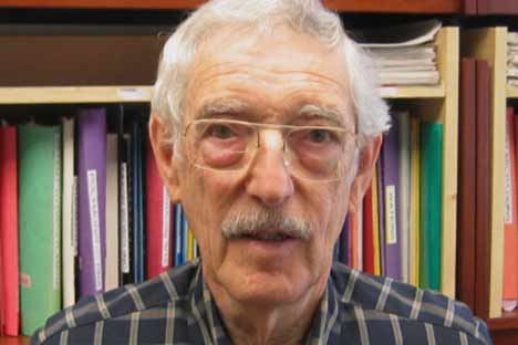 Older man wearing glasses in front of bookshelf
