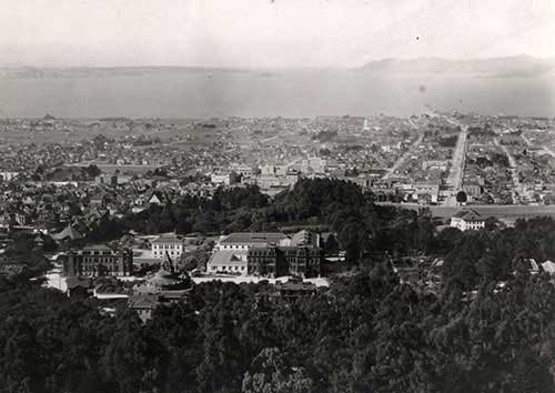 Historic photo of the campus from the hills east looking west with a view of the bay.