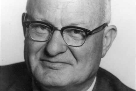 Black and white portrait photo of man wearing horn-rimmed glasses