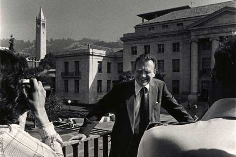 Man wearing suit standing on balcony with Sproul Hall in background