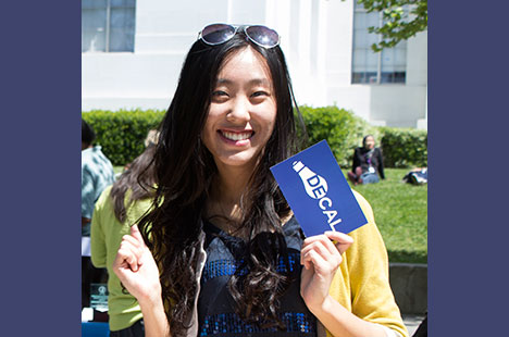 Asian woman holding a blue card with an image of a lightbulb and the text DeCal