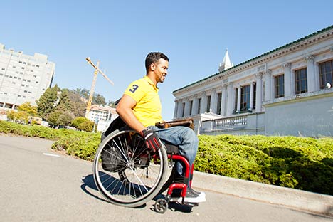 Male in wheelchair with Doe Library in background
