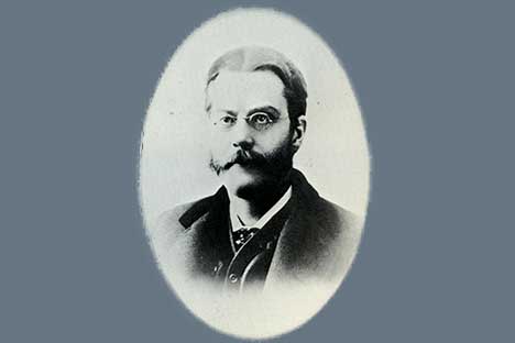 oval framed black and white portrait of mustachioed man wearing wire rimmed glasses