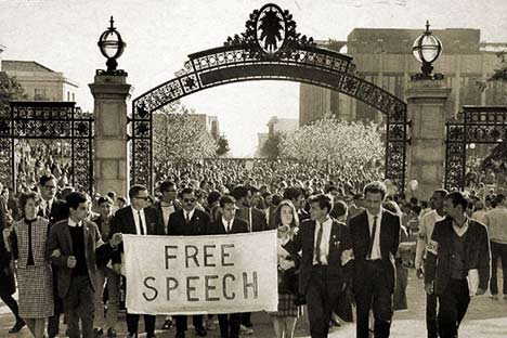 Historic photo ph crowds of marchers holding 'Free Speech' banner walking through Sather Gate