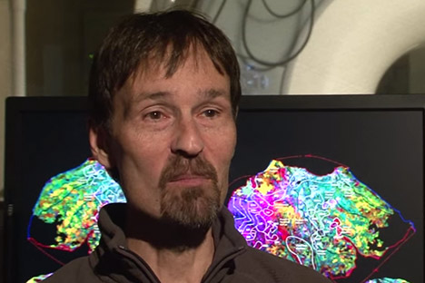 Bearded man sitting in front of a computer screen with visual display of brain waves