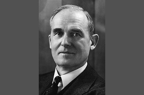 Black and white portrait photo of man wearing dark suit and tie