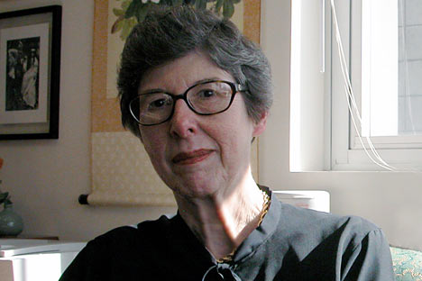 Color photo of older woman wearing horn-rimmed glasses
