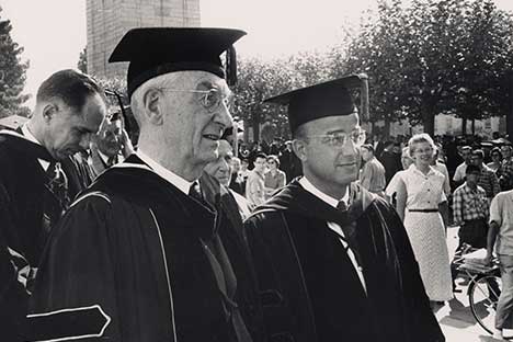 Two figures wearing scholars robes with mortarboards