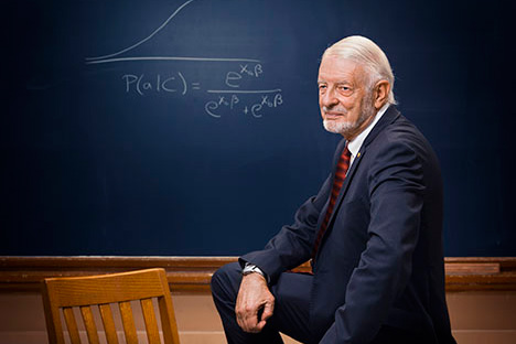 Man with leg on chair in front of blackboard with diagram
