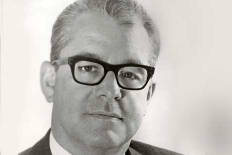 Man wearing dark horned rimmed glasses looking back at viewer