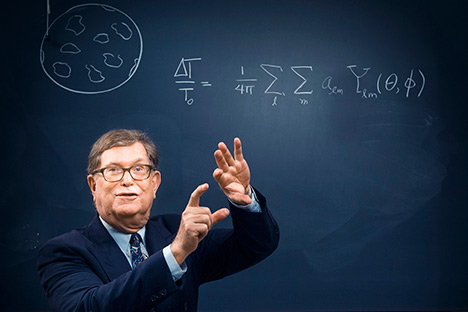 Man using his hands in during explanation with blackboard diagram in background