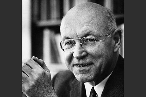 Black and white portrait photo of balding man with wireframe glasses