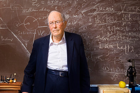 Man wearing blue jacket standing in front of chalkboard