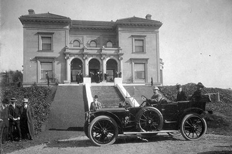 Historic photo of automobile in front of large mansion