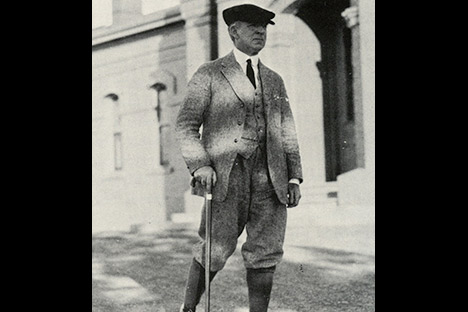 Black and white photo of man with a cane outdoors in front of a building