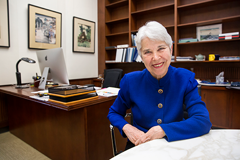 Woman wearing blue long sleeved suit with silver hair smiling back at viewer